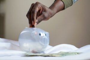 grant sabatier person putting coin in a translucent piggy bank