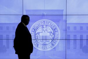 inflation hedge silhouette of a large man standing in front of nine screen with the federal reserve image and building on it