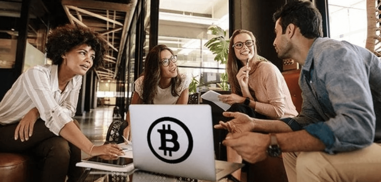 weekly crypto news group of people around a laptop with the bitcoin logo on it for decentral publishing